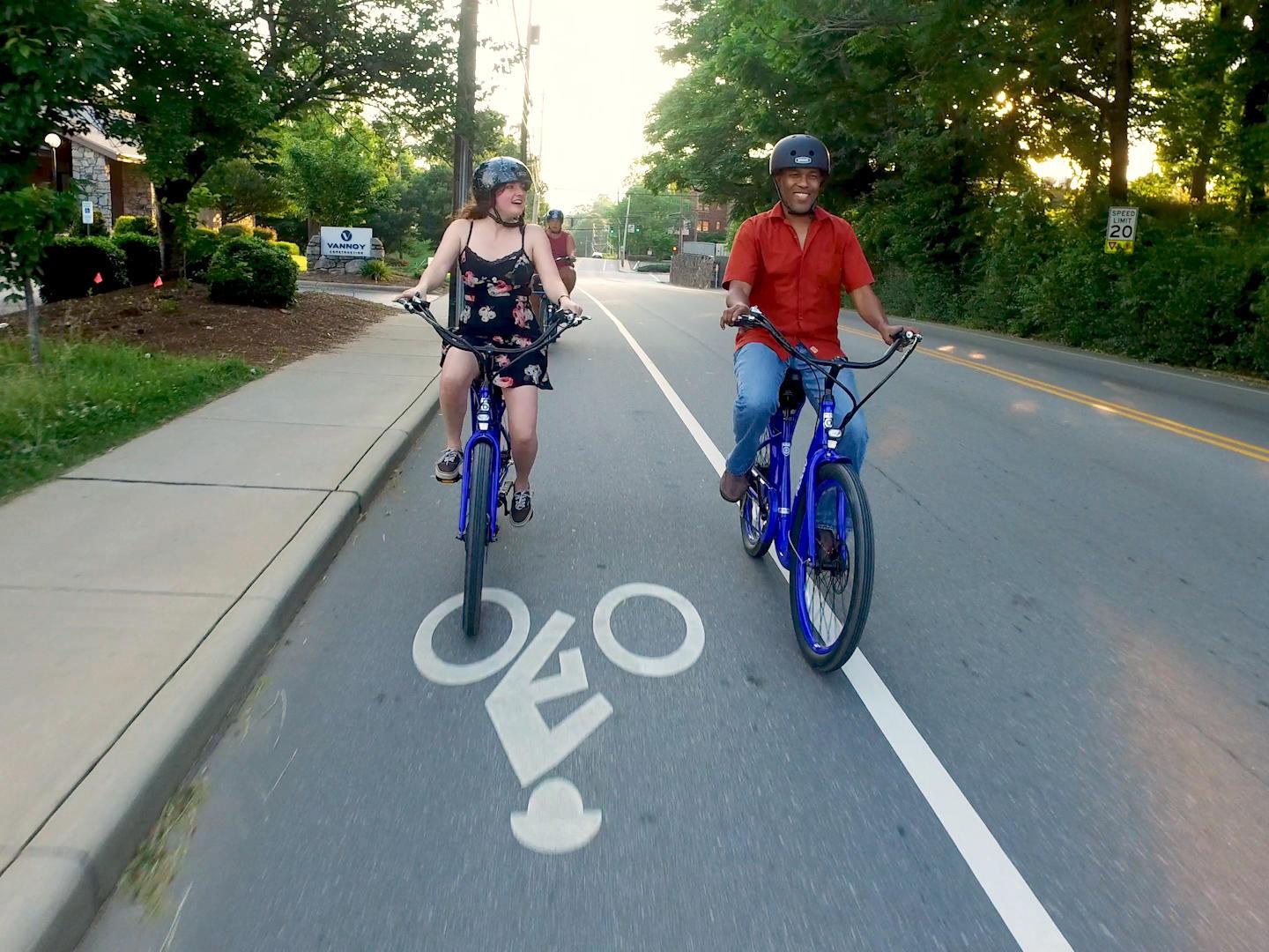 Two people riding bicycles in a bike lane on the side of a cyclist-friendly road in Asheville, NC