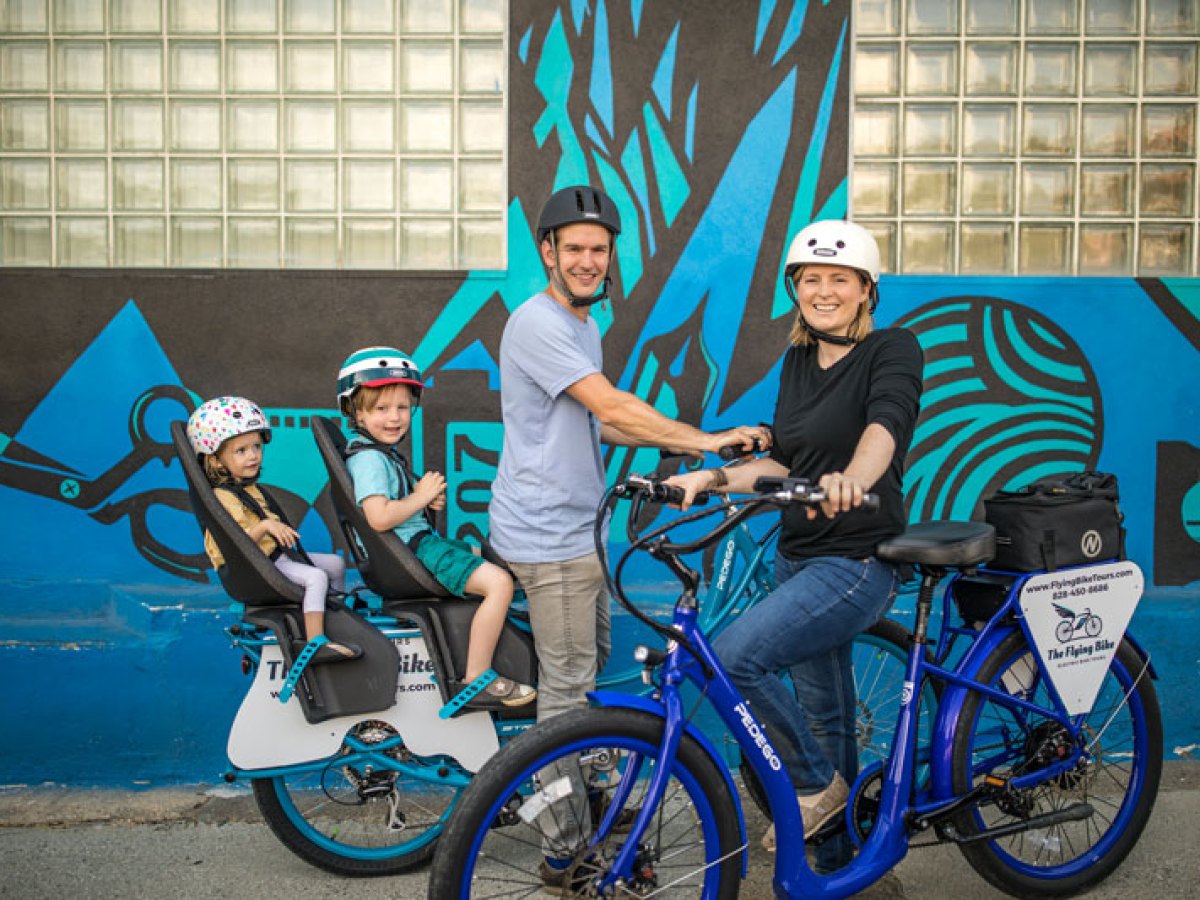 Family with two kids smiling during their kid-friendly bike tour through Downtown Asheville, NC